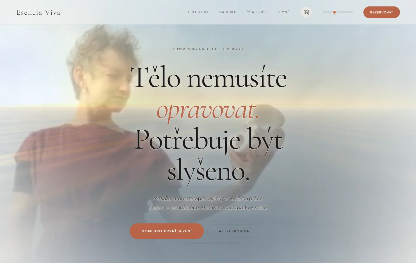The Esencia Viva homepage: a pale, washed-out photograph of a woman standing by water fills the screen behind large serif type reading "Tělo nemusíte opravovat. Potřebuje být slyšeno." — the body does not need fixing, it needs to be heard. Below it a line about massage, aromatherapy, herbs and conscious body work, and two buttons — arrange a first session, and how it works.